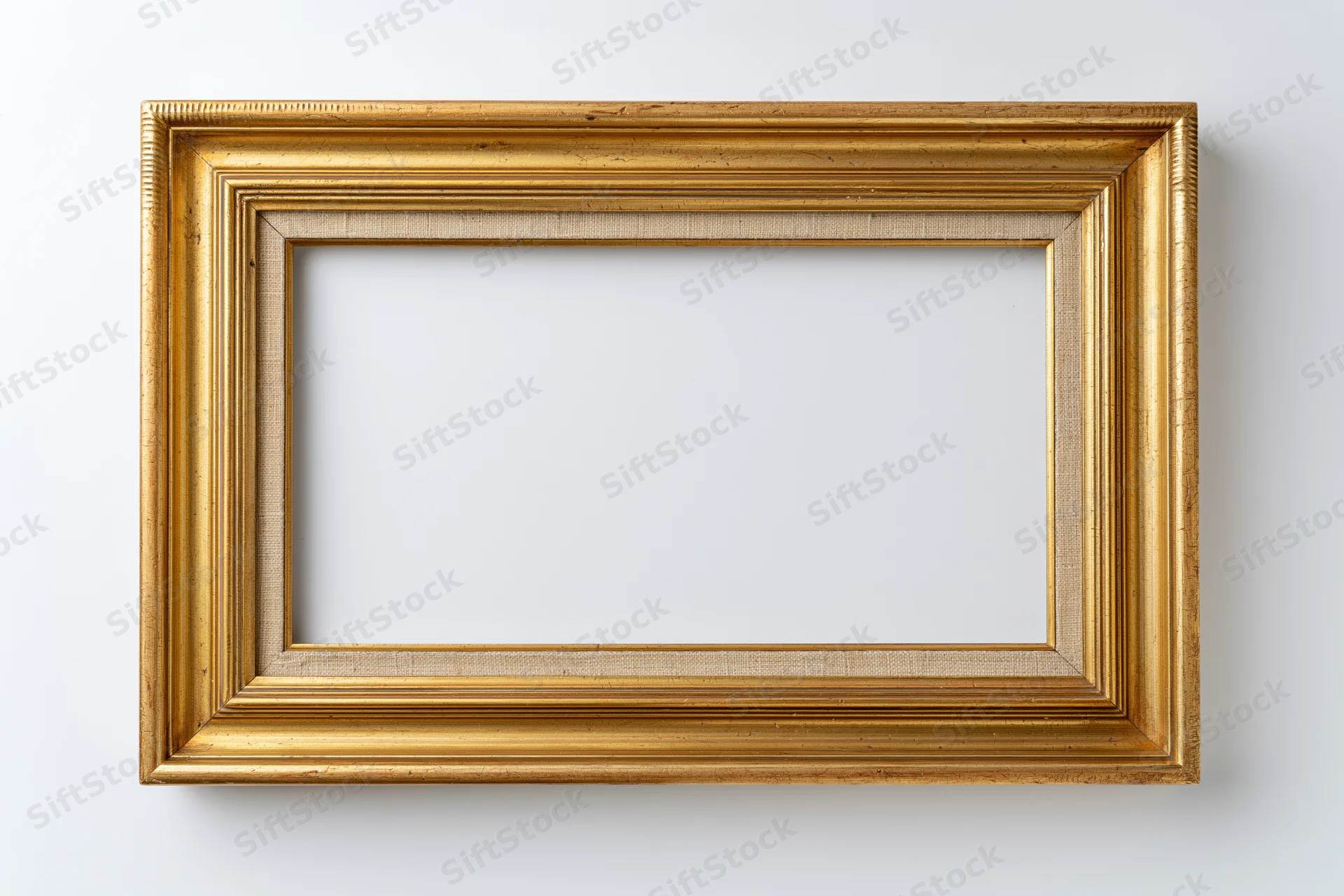 Empty antique gold picture frame hanging on white wall