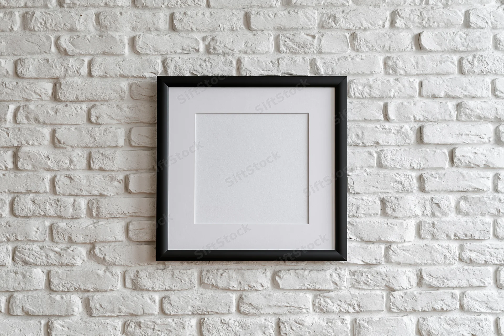 Black picture frame with white mat hanging centered on white brick wall