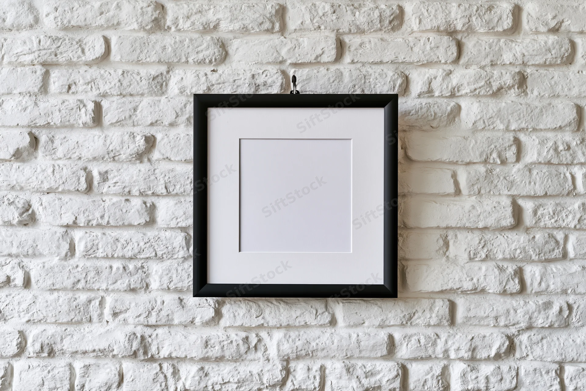 Black picture frame with white mat hanging centered on white brick wall