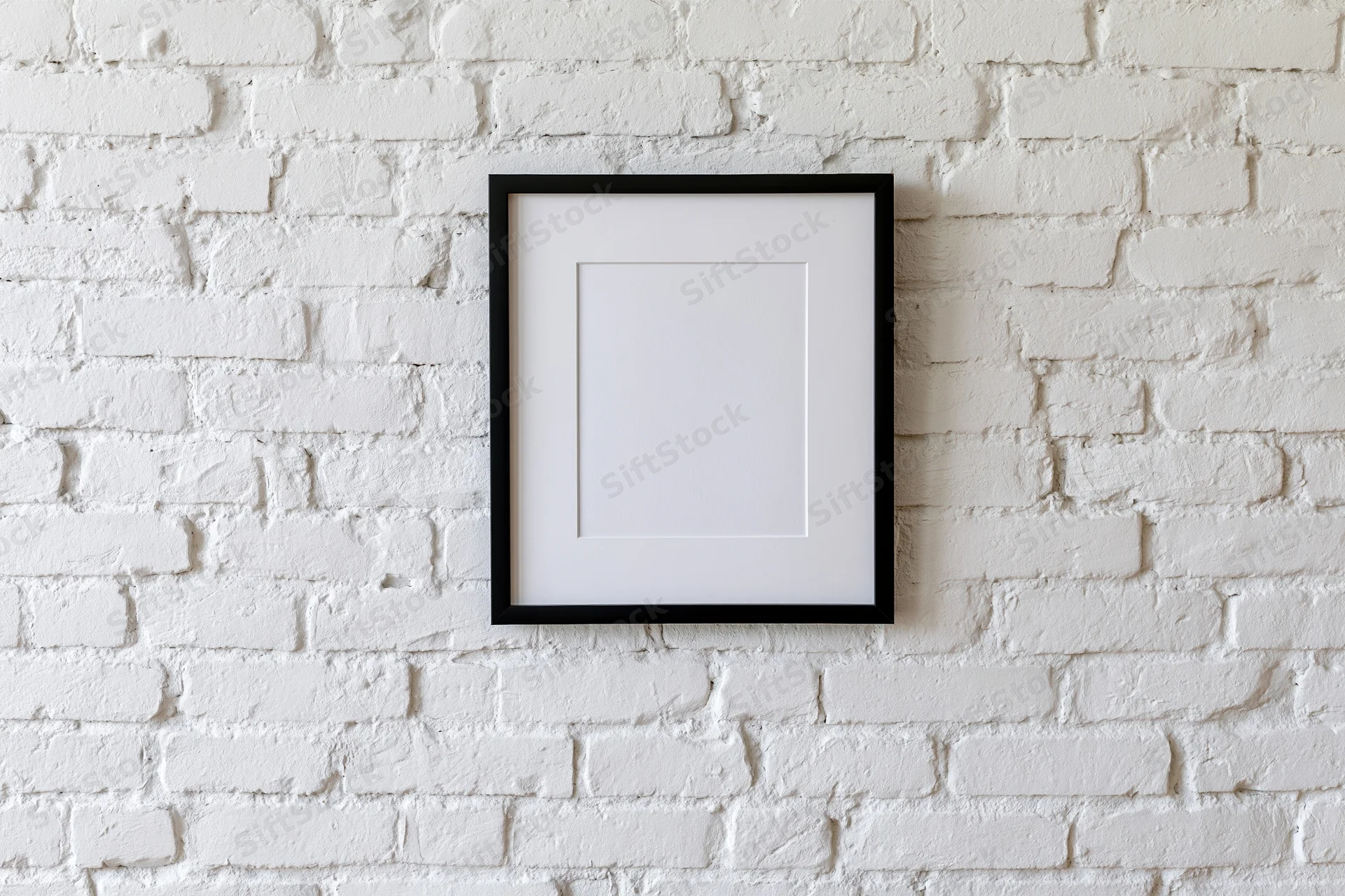 Black picture frame with white mat hanging centered on white brick wall