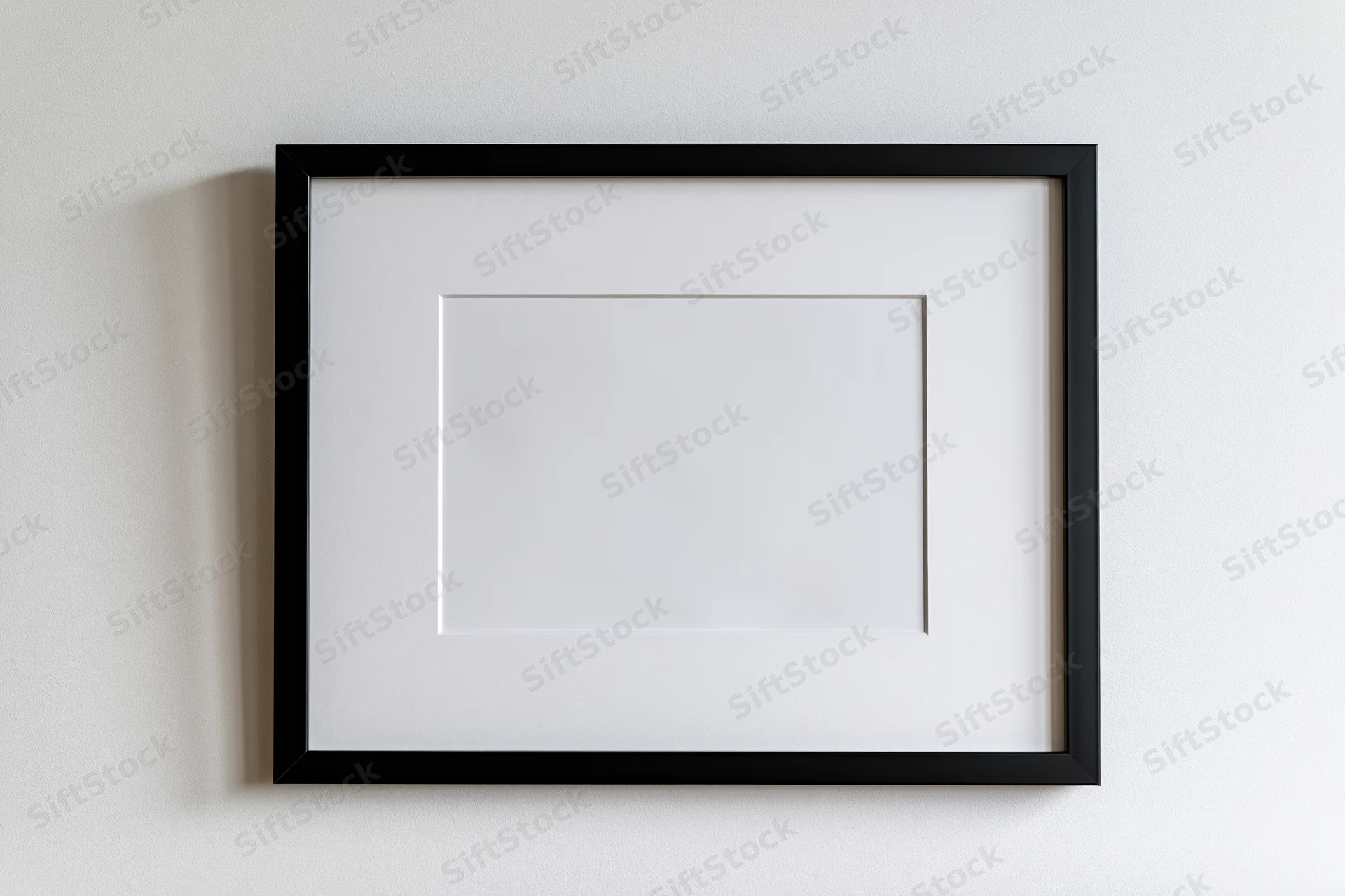 Black picture frame with white mat mounted flat on a white wall