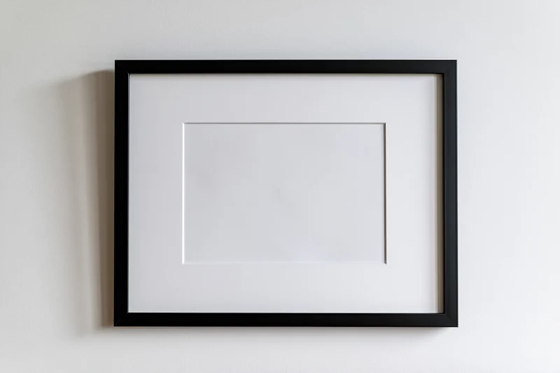 Black picture frame with white mat mounted flat on a white wall