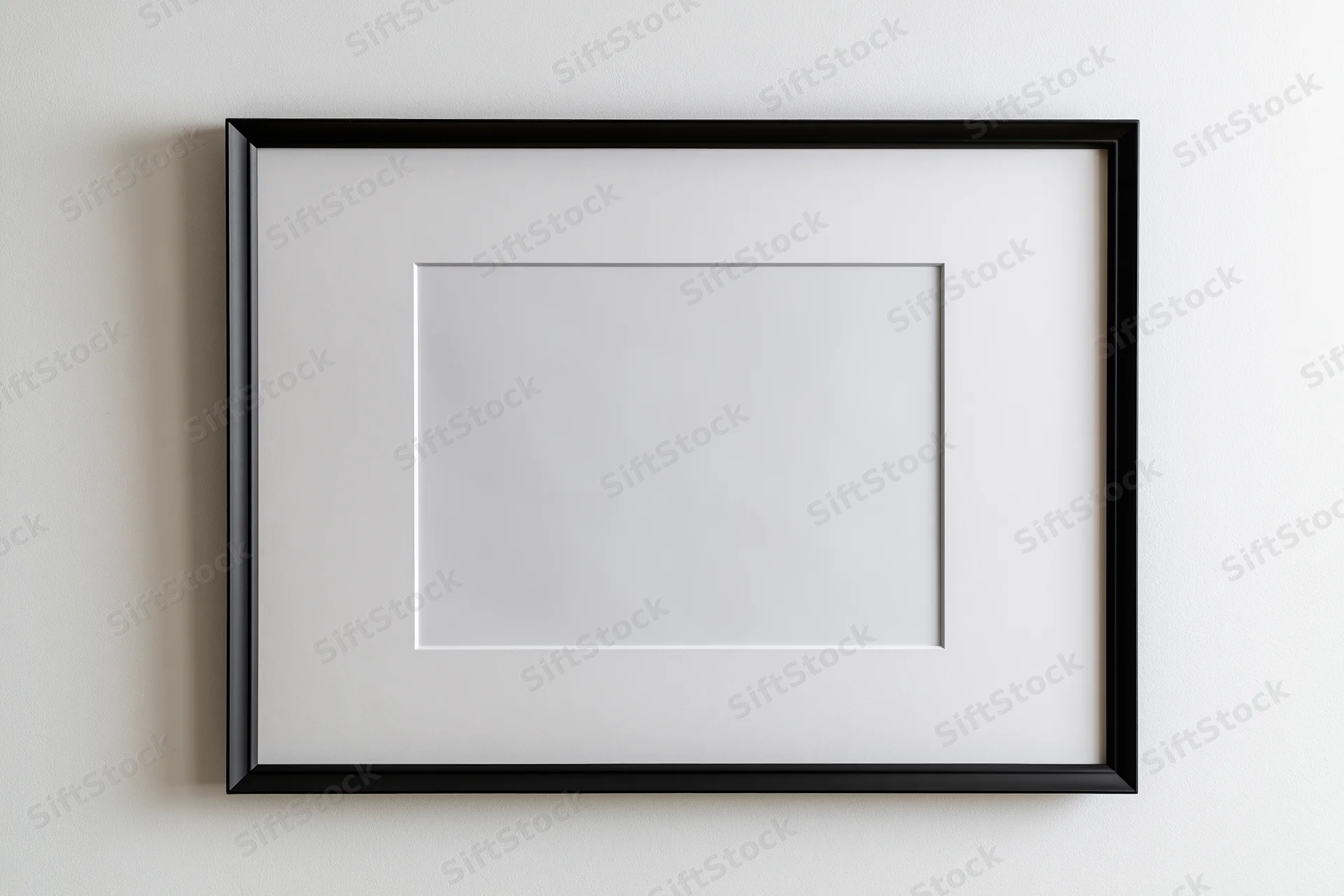 Black picture frame with white mat mounted on white wall, empty interior space for artwork display
