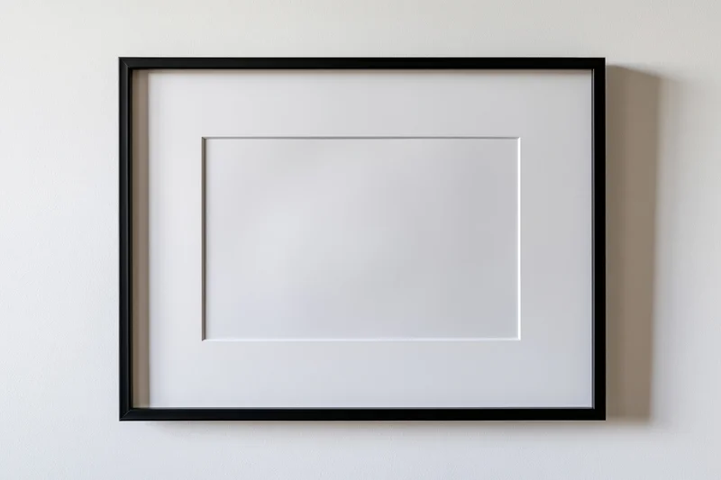 Black picture frame with white mat mounted flat on a white wall