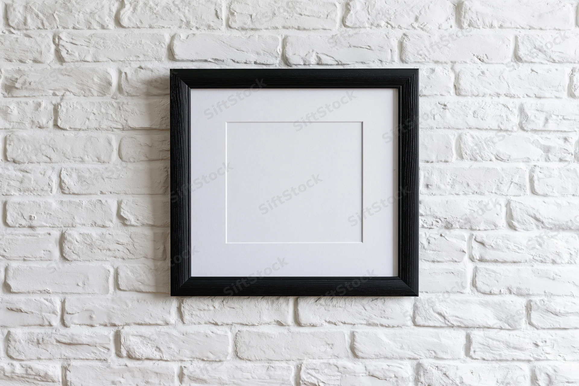 Black wooden picture frame with white mat hanging on white brick wall
