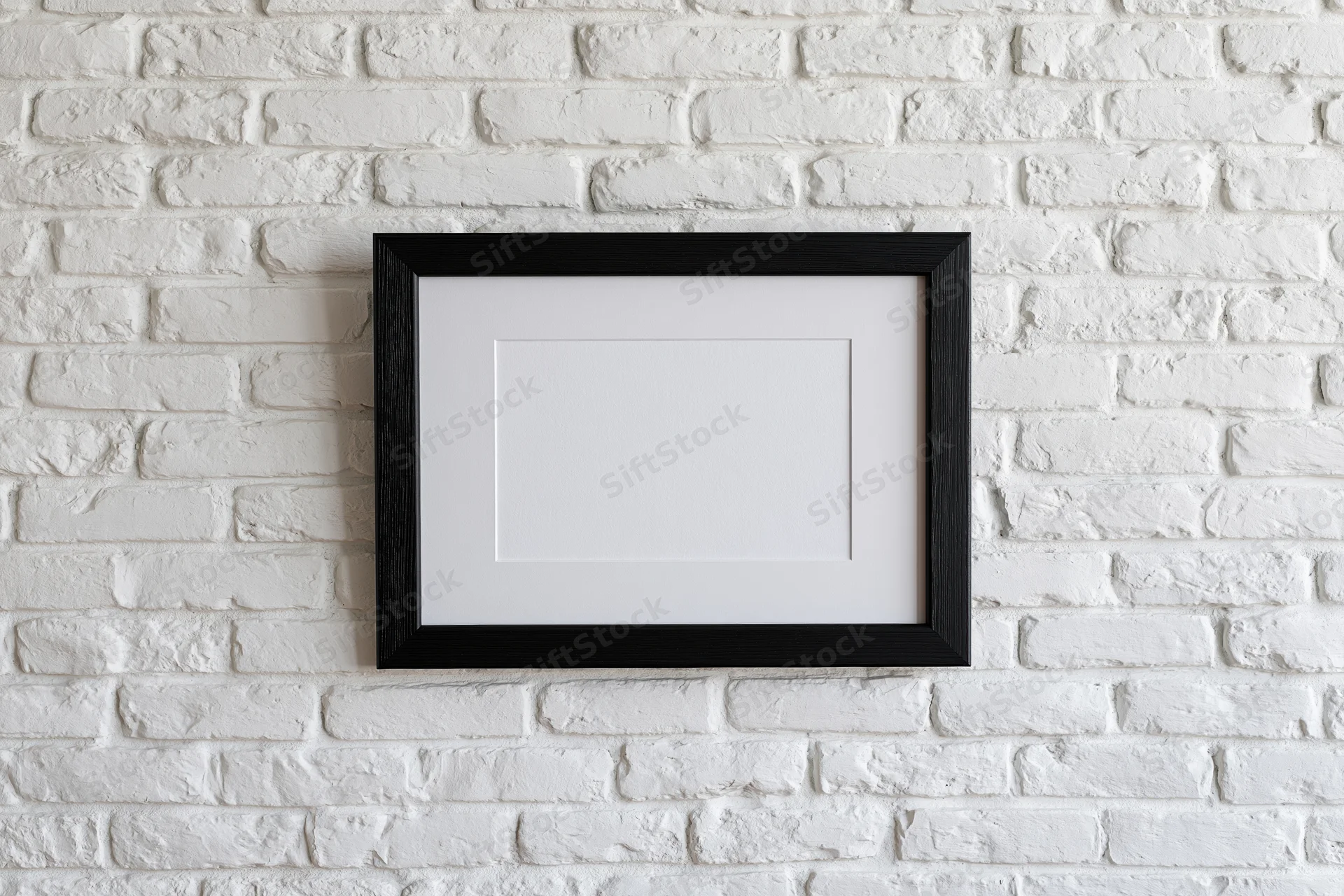 Black wooden picture frame with white mat hanging on white brick wall