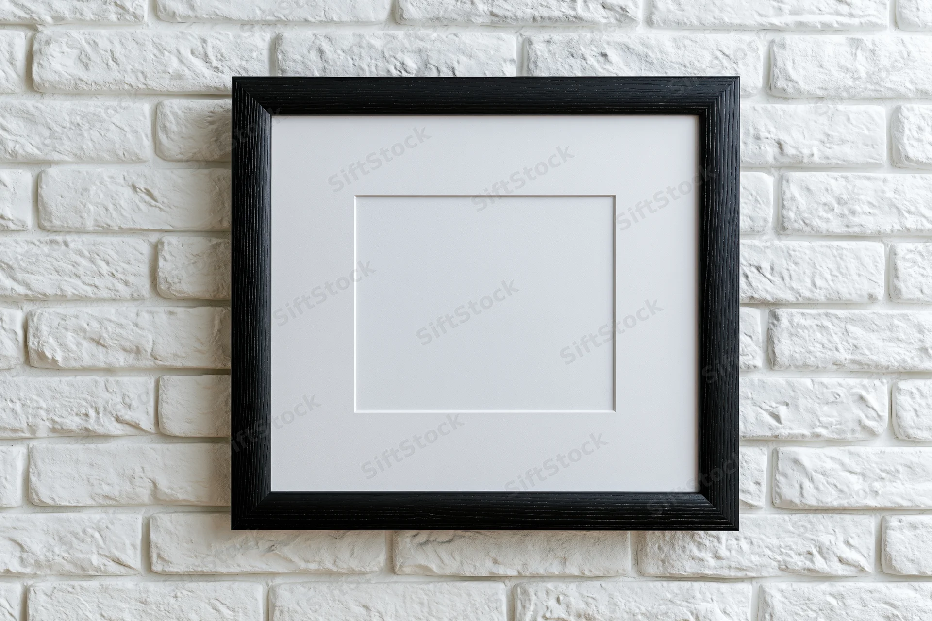 Black wooden picture frame with white mat hanging on white brick wall