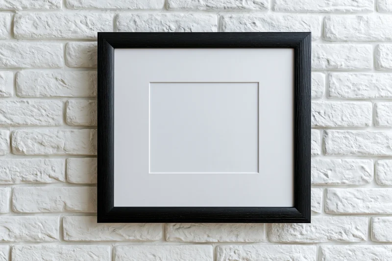 Black wooden picture frame with white mat hanging on white brick wall