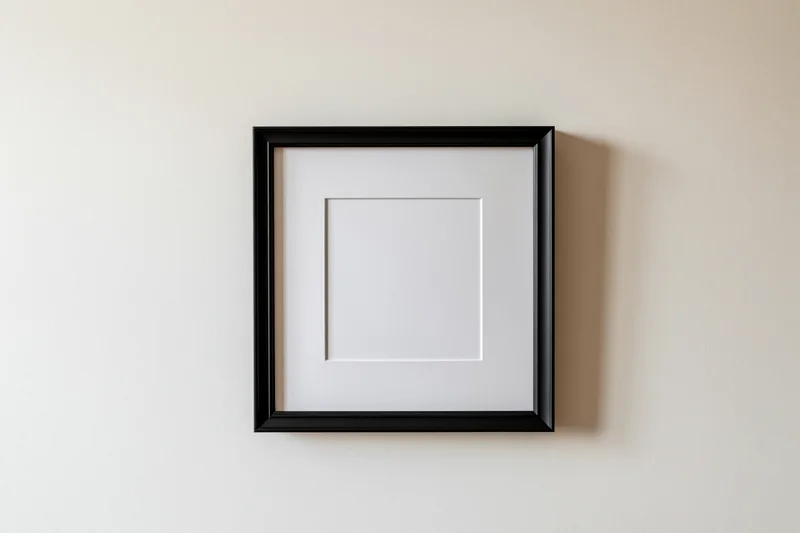Black square frame with white mat mounted flush on a beige wall