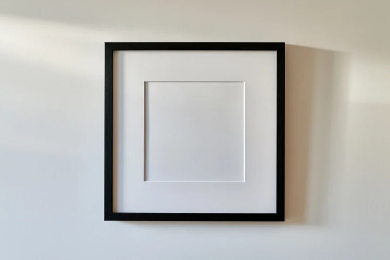 Black square frame with white mat mounted flush on a white wall