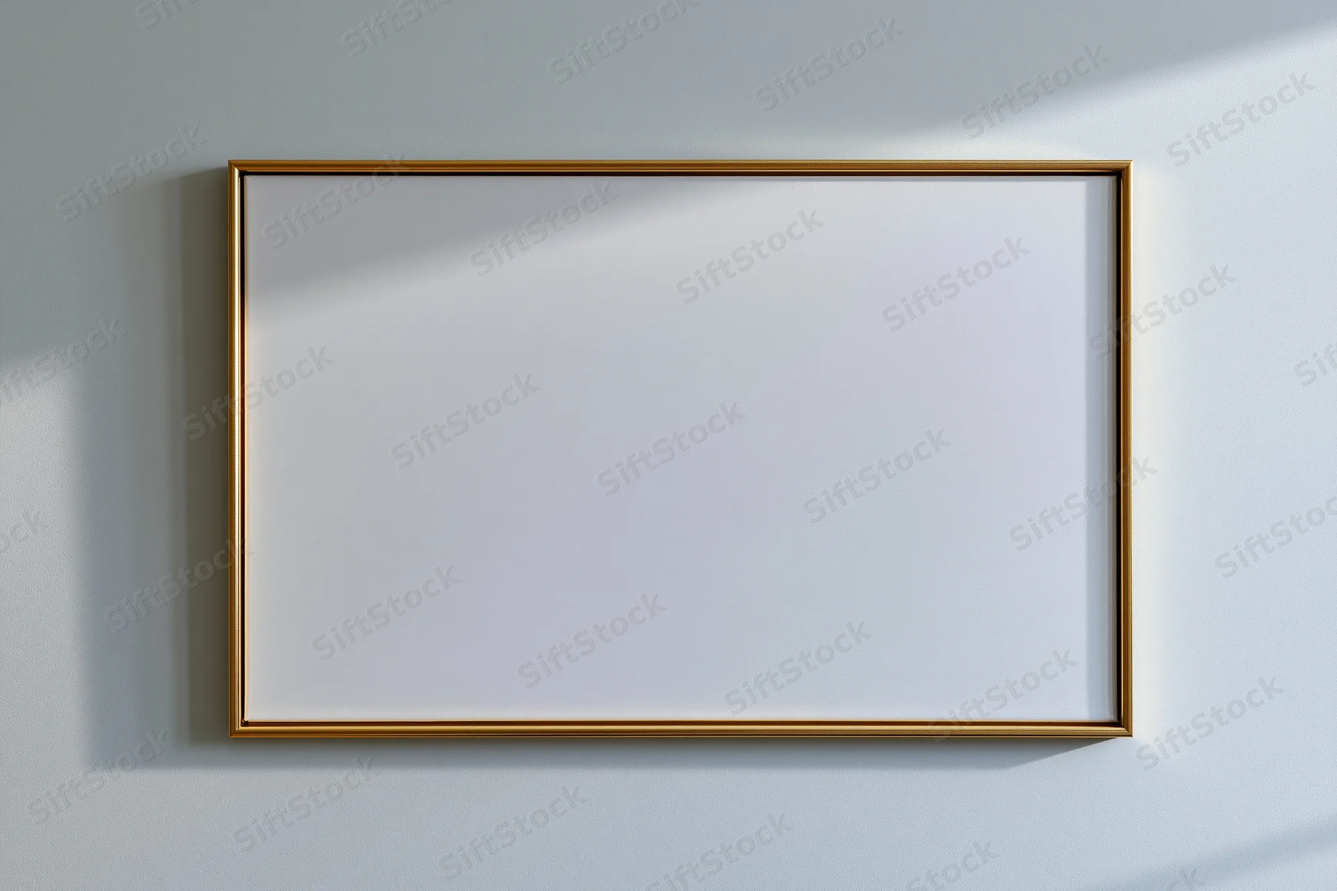 Gold-framed blank canvas hanging on a white wall with soft shadows
