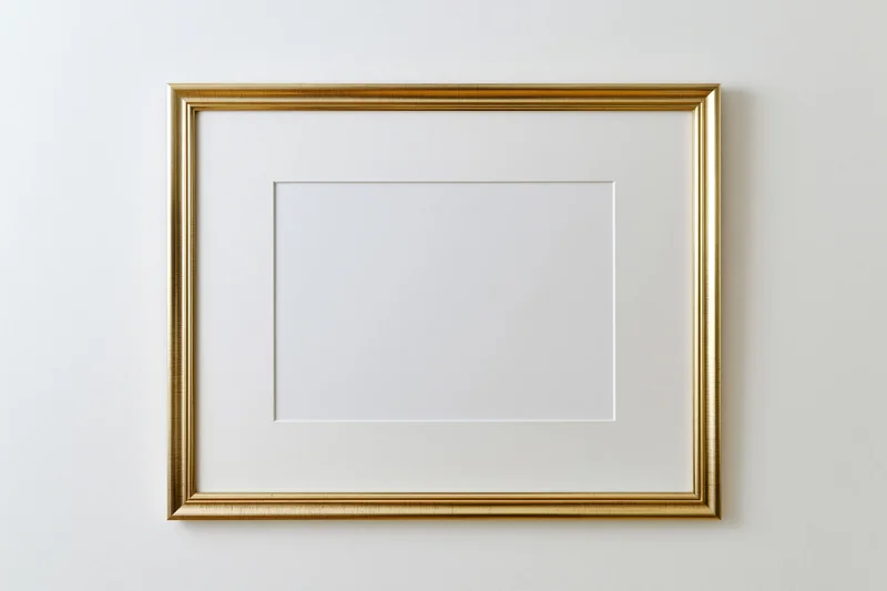 Gold picture frame with blank white interior mount hanging on a white wall
