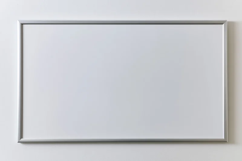 Empty white dry-erase board with thin aluminum frame mounted on white wall