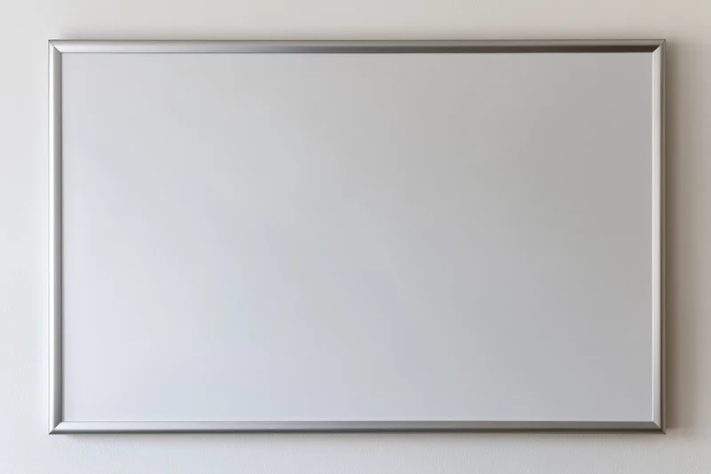Empty white dry-erase board with thin brushed aluminum frame mounted on a white wall