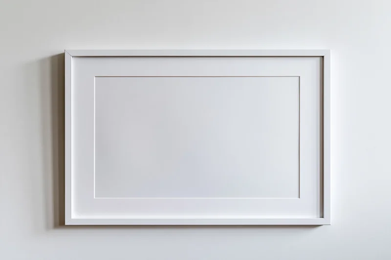 White picture frame with mat border hanging on a plain wall