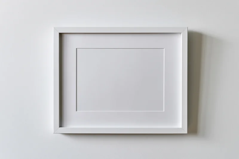 White picture frame with mat border hanging on a plain wall