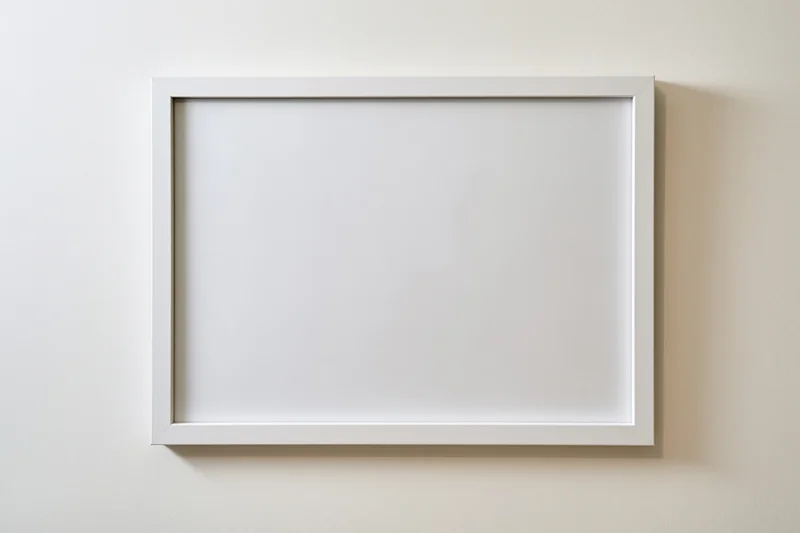 White empty picture frame mounted on off-white wall