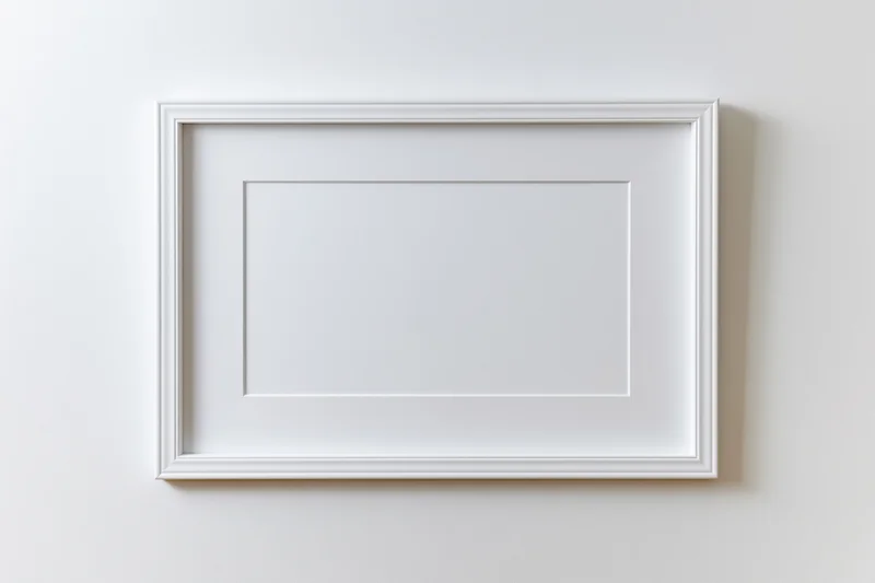 White rectangular picture frame with thin molded border hanging on a plain wall