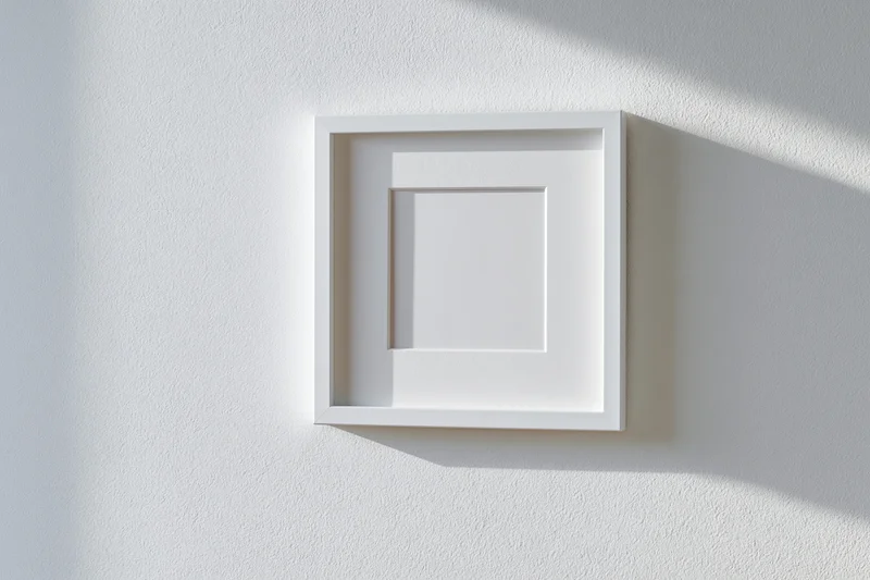 White square picture frame with wide mat hanging on a textured wall