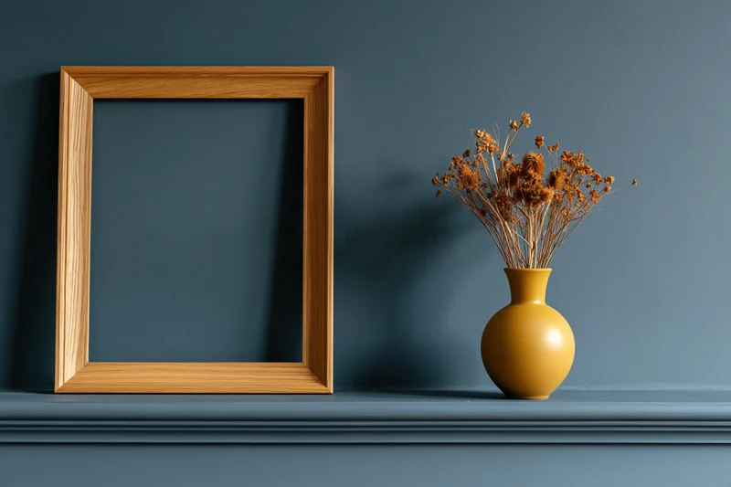 Empty wooden frame leaning on a blue shelf beside a mustard vase with dried flowers