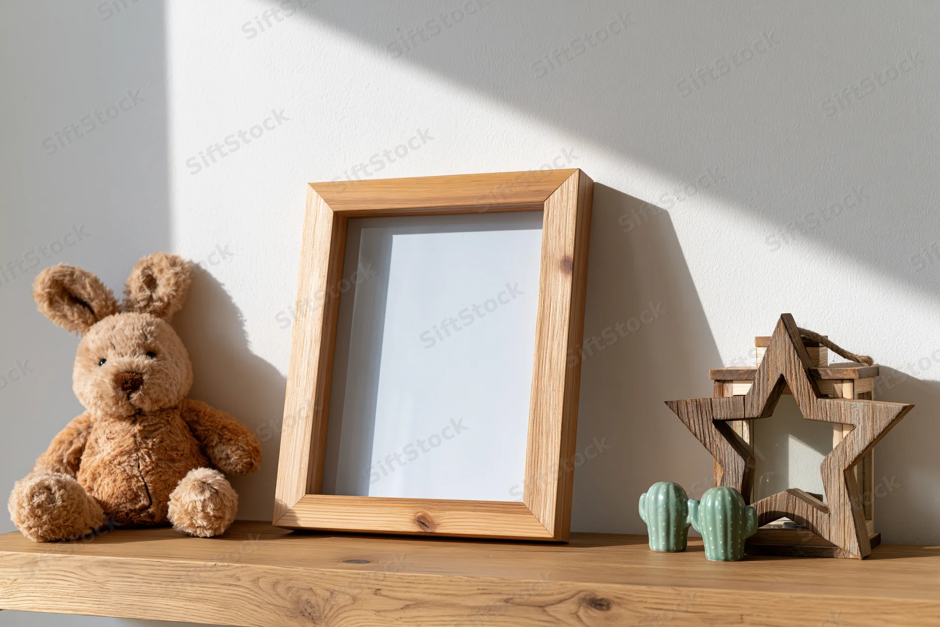 Empty wooden picture frame leaning on a shelf beside a stuffed bunny and decorative items