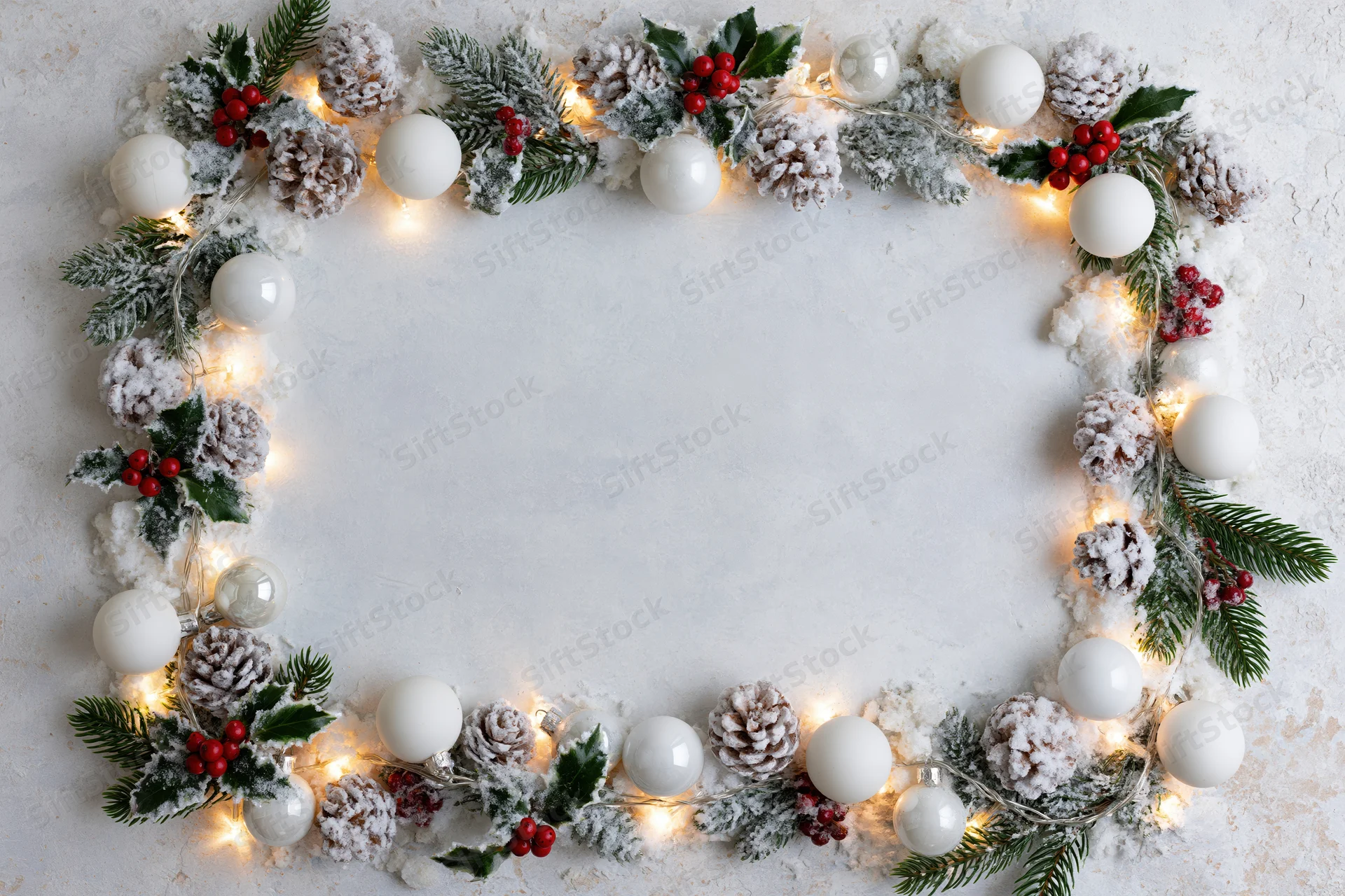 Christmas decoration border with pinecones, holly, lights and ornaments on white surface