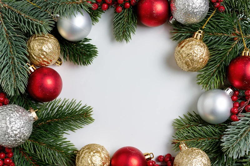 Christmas wreath border made of fir branches and ornaments arranged in a frame on white background with copyspace