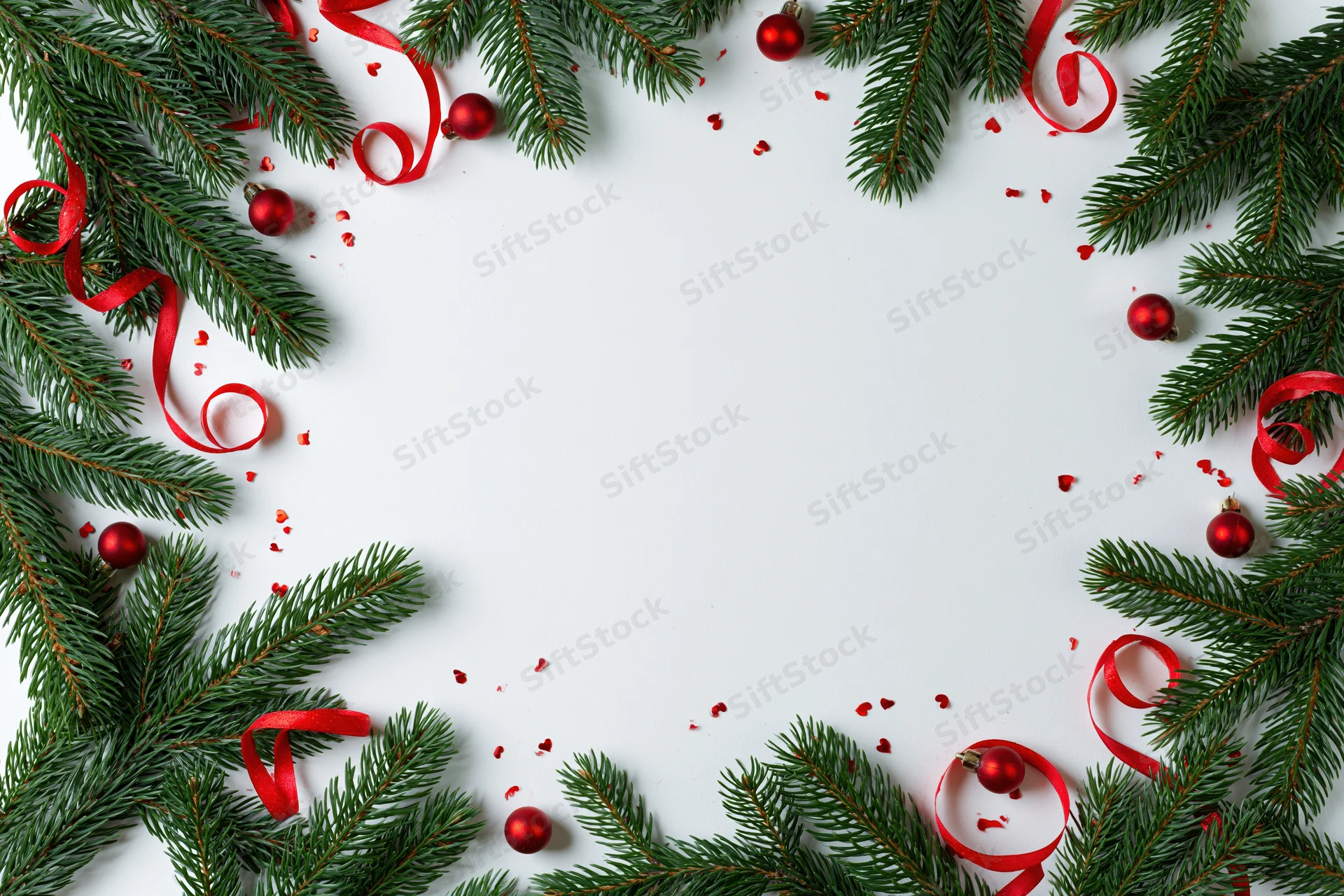 Fir branches and red ribbons arranged as a christmas border frame on white surface with copyspace