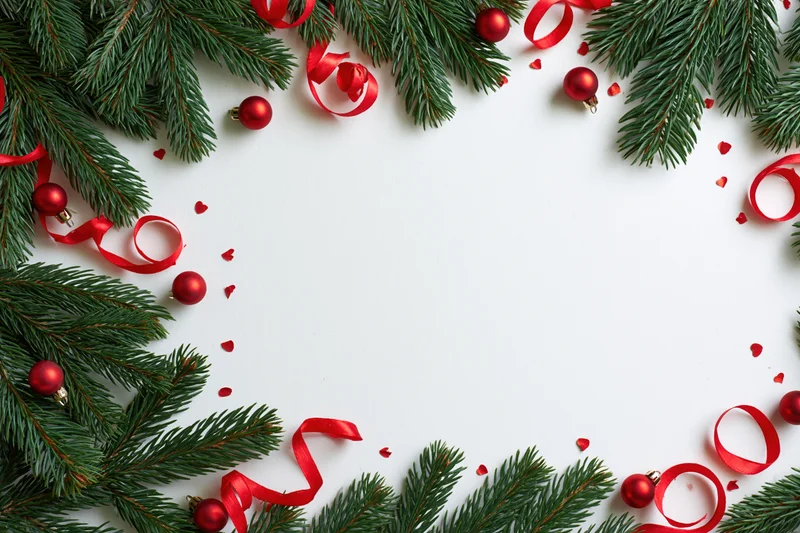 Christmas border frame made of green fir branches and red ornaments on white background with copyspace