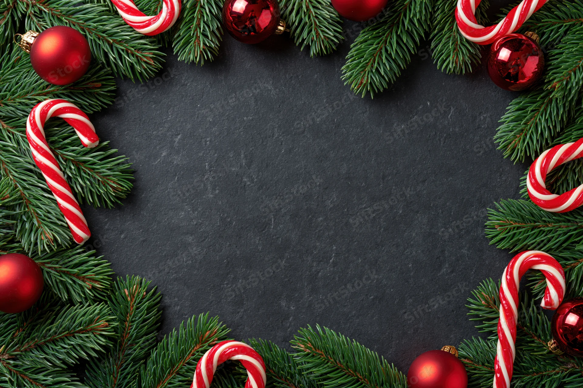 Christmas border frame made of pine branches and ornaments on dark surface with copyspace