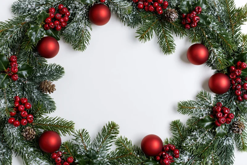 Christmas border frame made of pine and fir branches with red ornaments and holly berries on white background