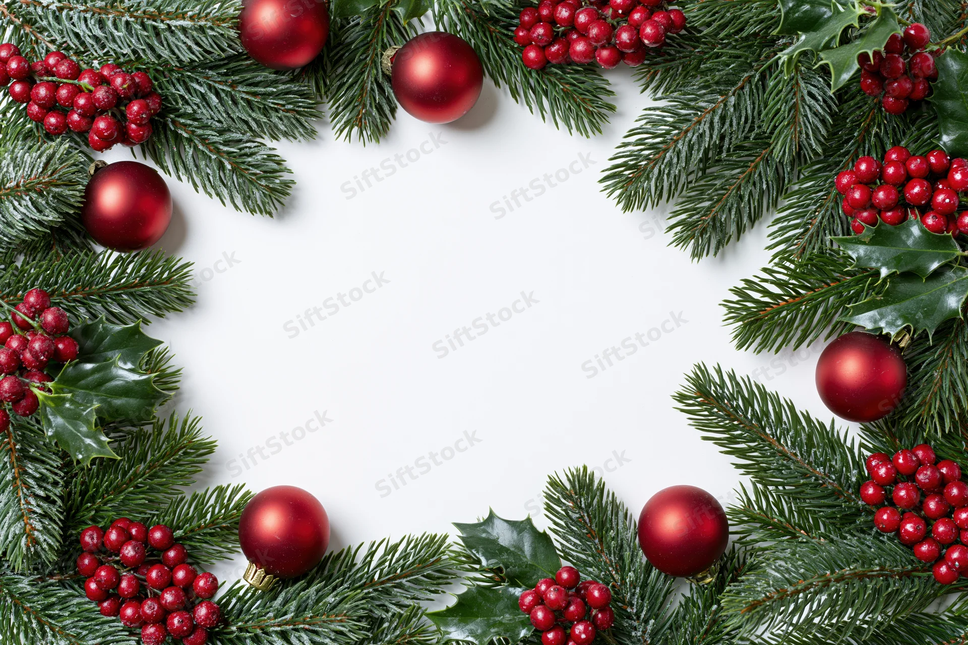Pine branches and red ornaments arranged in a circular frame on white background with copyspace