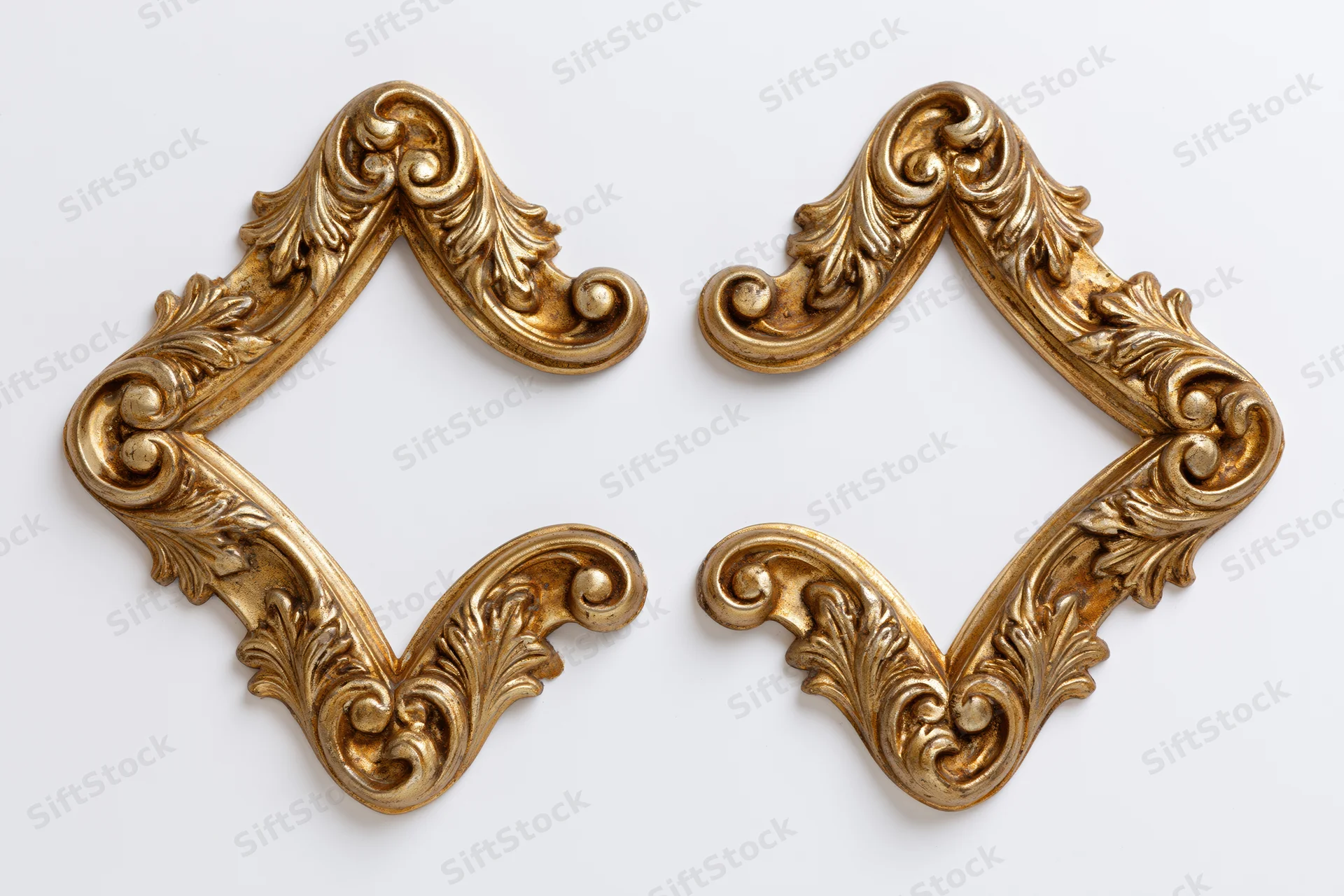 Two ornate gilded baroque corner pieces arranged symmetrically on white background