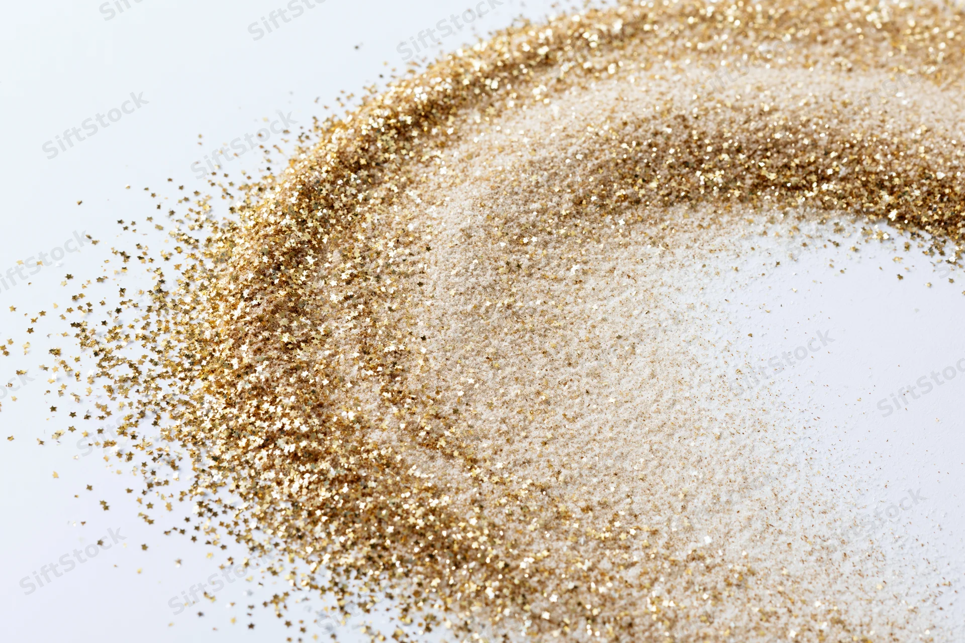 Gold glitter dust scattered in a circular pattern on white surface