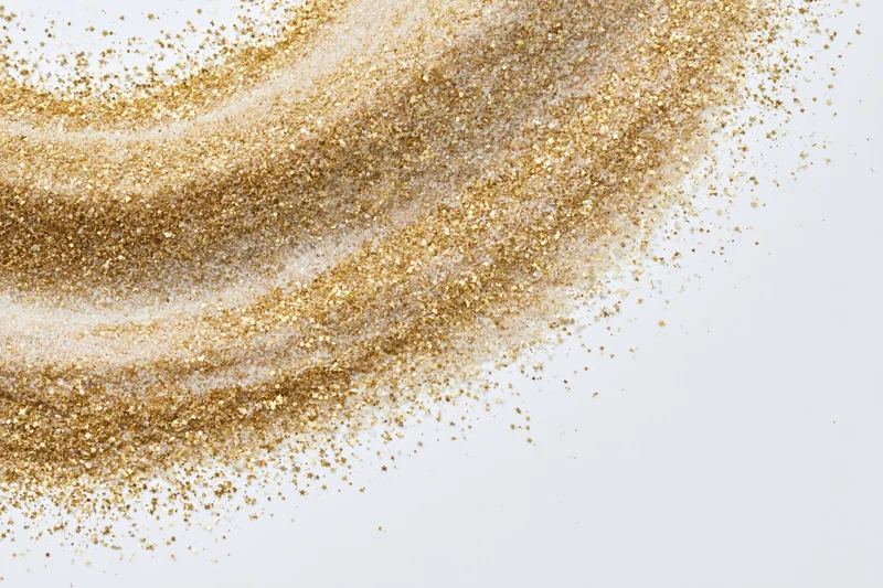 Gold glitter dust scattered across a white surface with copyspace on the right