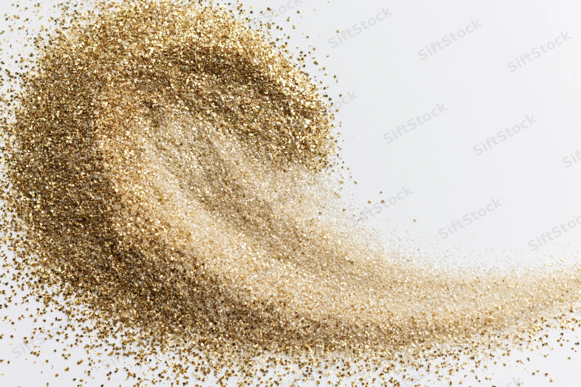 Gold glitter dust scattered across a white surface with copyspace