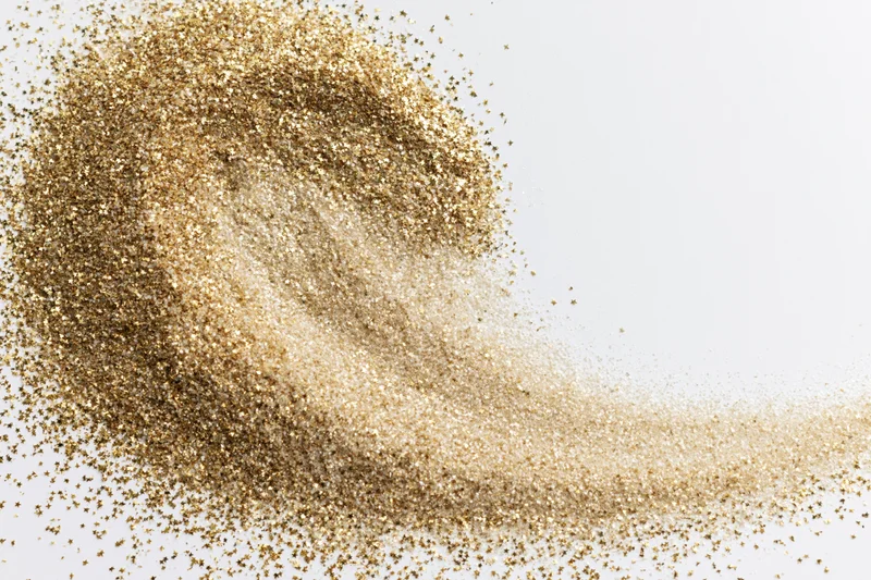 Gold glitter dust scattered across a white surface with copyspace