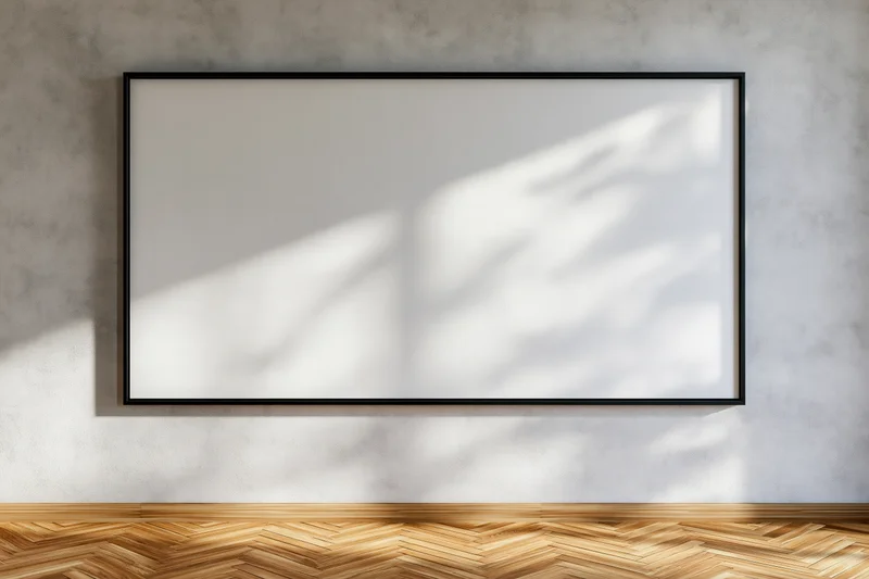 Black-framed blank canvas hanging on concrete wall above wooden parquet floor