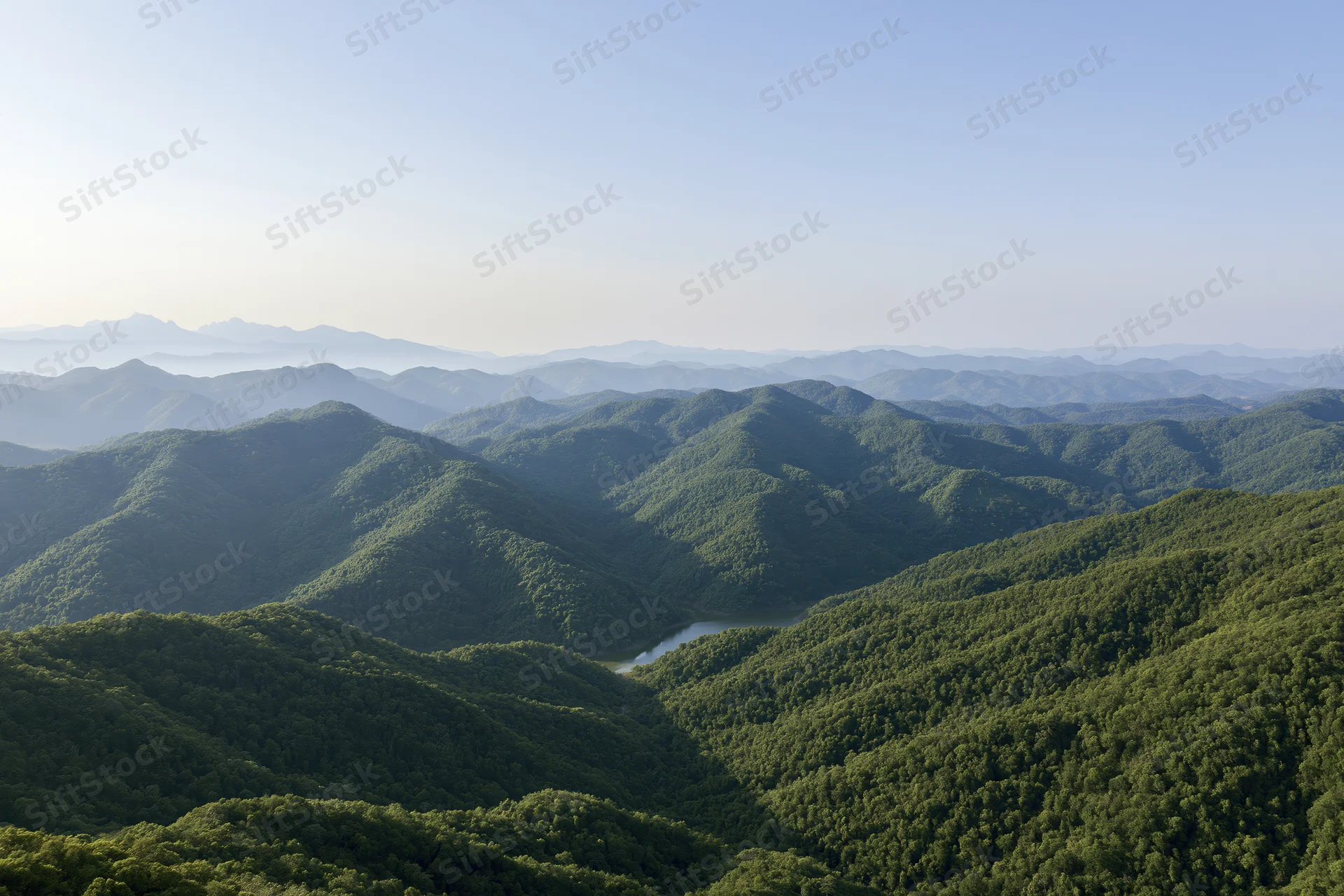 Aerial view of layered green mountain ridges stretching to the horizon