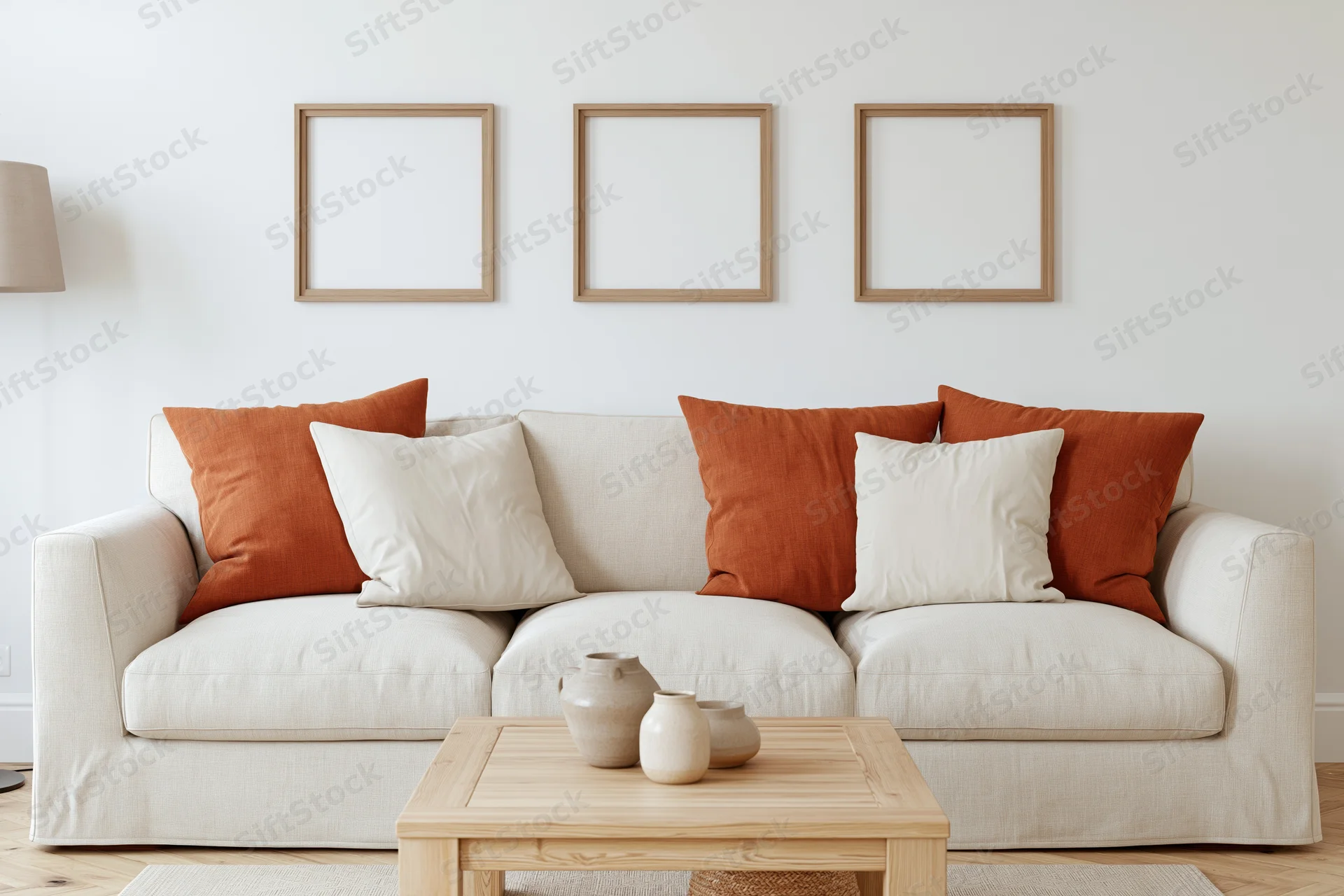 Cream linen sofa with orange and beige cushions in a minimalist scandinavian living room with wooden coffee table and empty wall frames