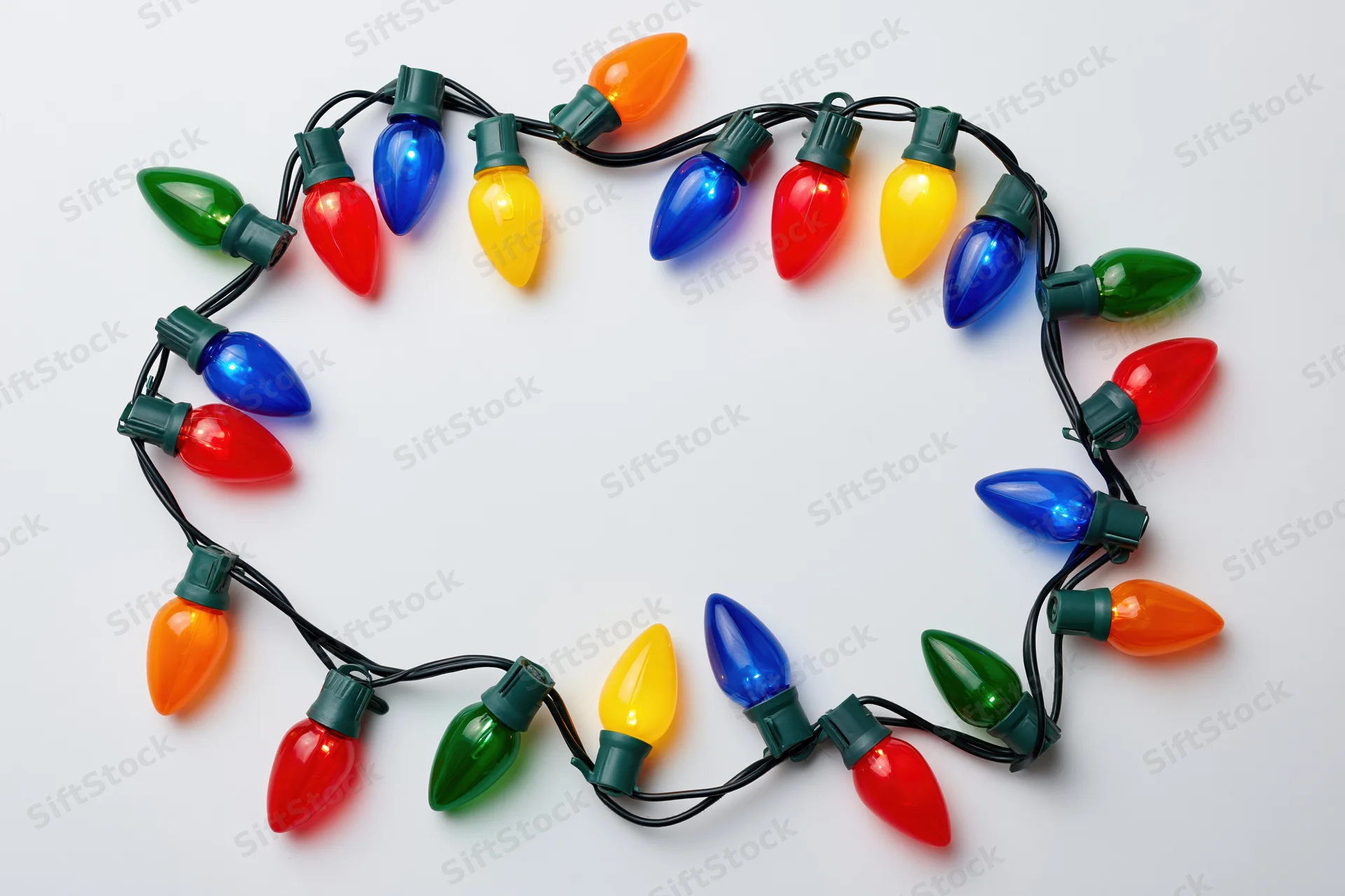 Multicolored christmas string lights arranged in a circular frame on white background