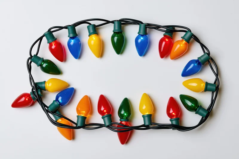 Multicolored christmas string lights arranged in rectangle on white background