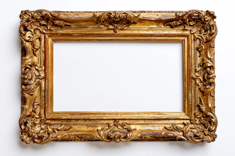 Ornate antique gold picture frame with baroque carvings photographed flat against white background