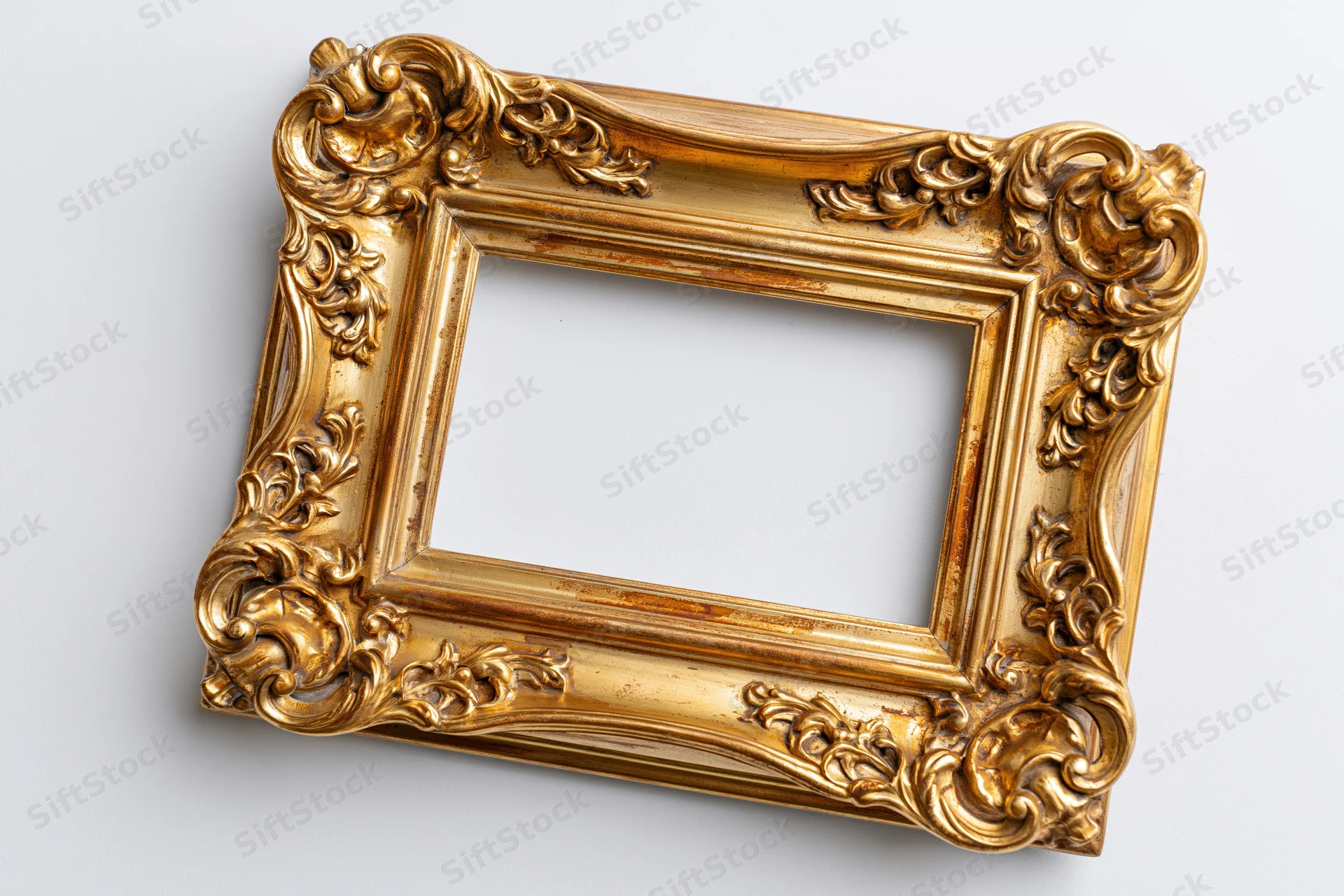 Ornate gold picture frame with baroque carved floral details on white background