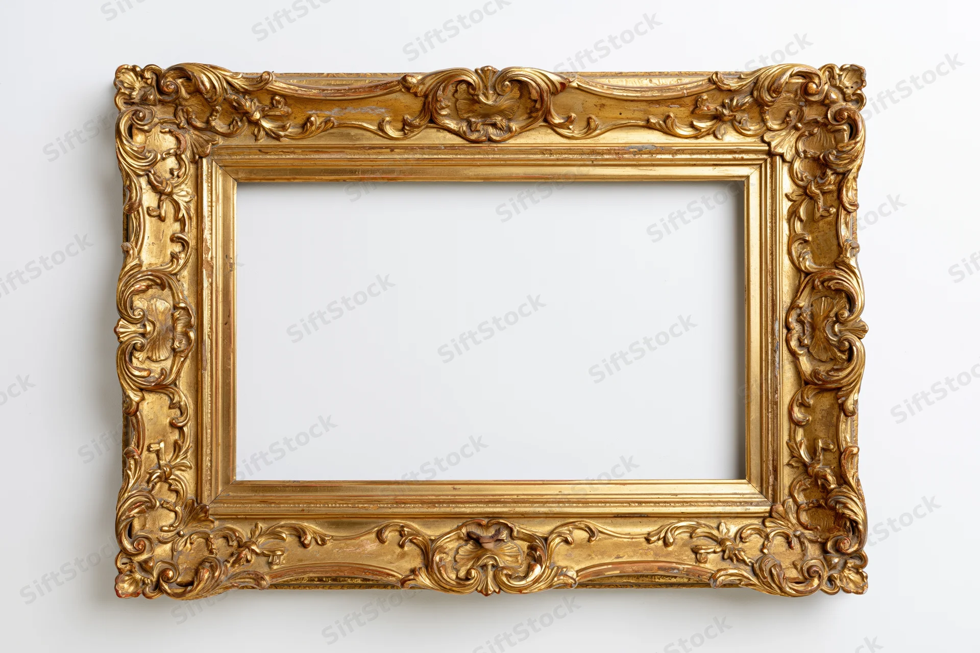 Ornate antique gold picture frame with baroque carved scrollwork hanging on white wall