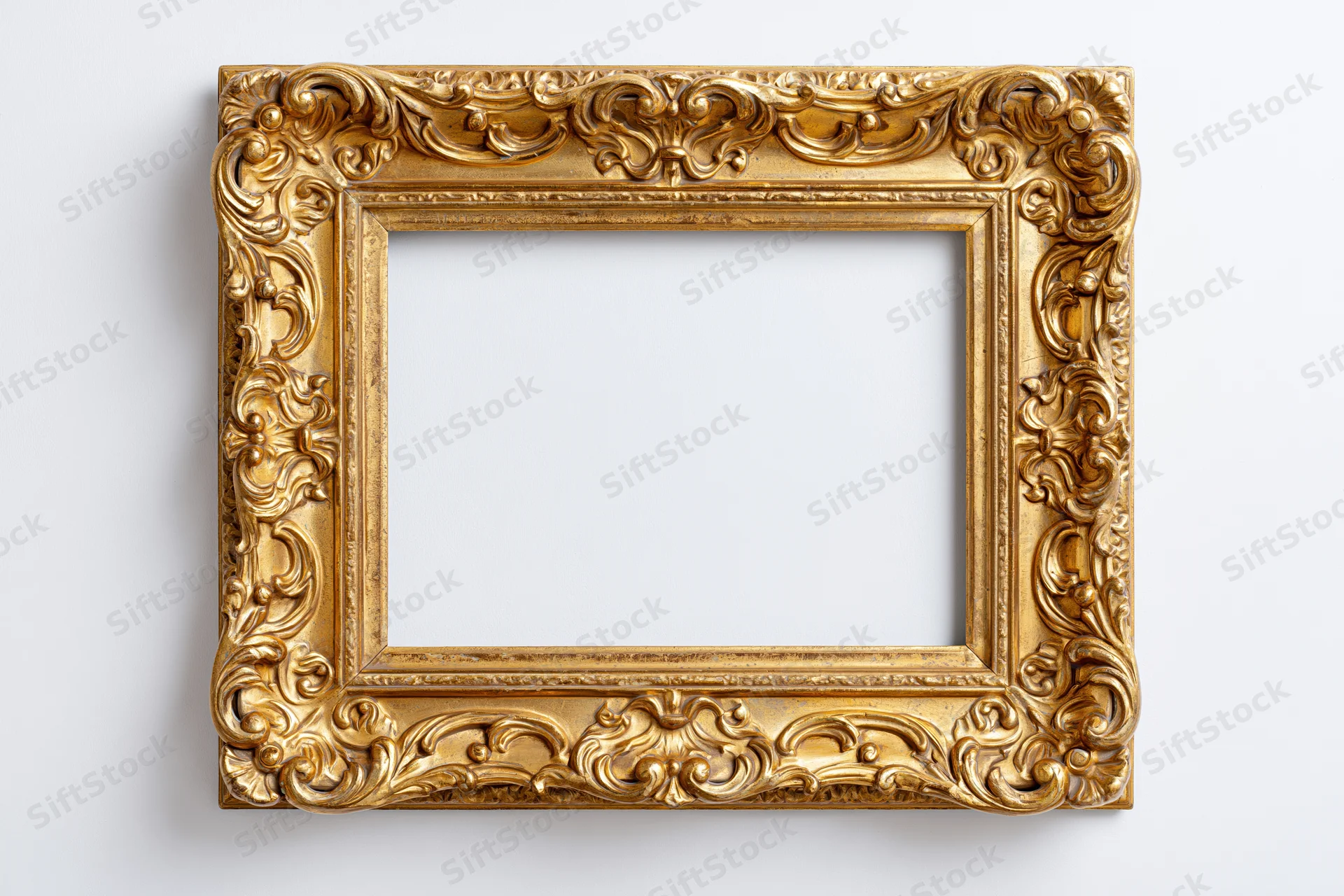 Ornate gold picture frame with baroque carved scrollwork hanging on white wall