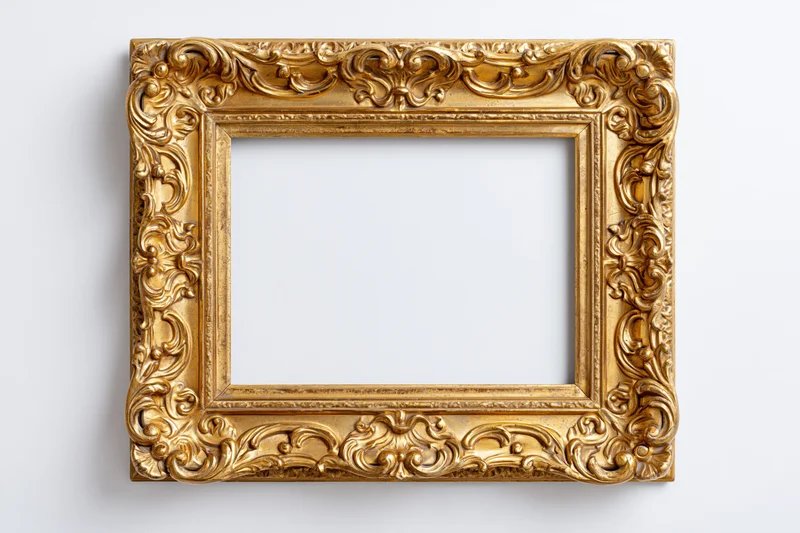 Ornate gold picture frame with baroque carved scrollwork hanging on white wall