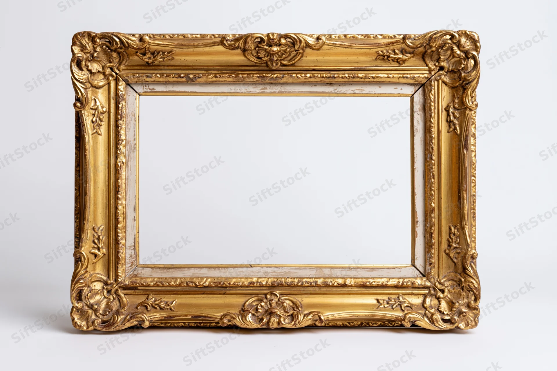 Ornate antique gold picture frame with baroque floral relief on white background