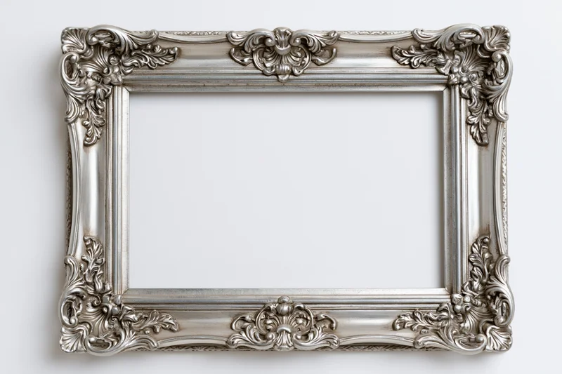 Ornate silver picture frame with baroque floral details hanging on a white wall