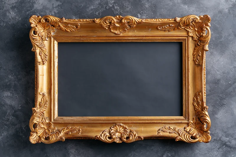 Ornate gold baroque frame with carved floral details on dark textured surface